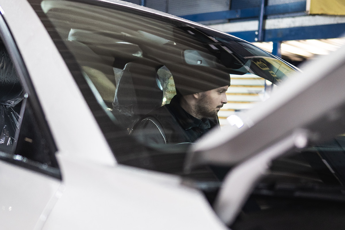KFZ Mechatroniker sitzt in einem Auto